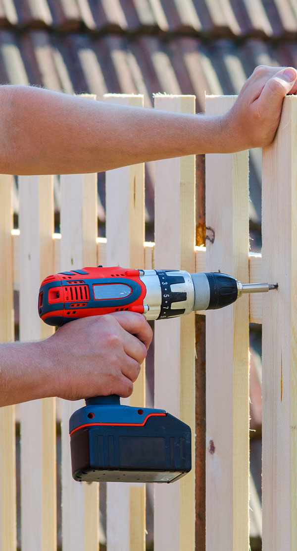 man-hands-building-wooden-fence-with-a-drill-and-screw-diy-concept-close-up-of-his-hand-and-tool-